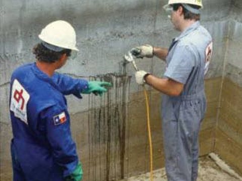 Technicians injecting resin into a leaking crack in a concrete wall